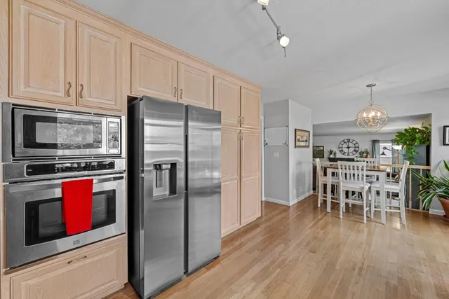 a kitchen with stainless steel appliances granite countertop a refrigerator microwave and wooden floor