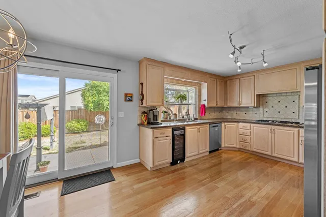 a kitchen with stainless steel appliances granite countertop a refrigerator a sink dishwasher a stove and white cabinets with wooden floor