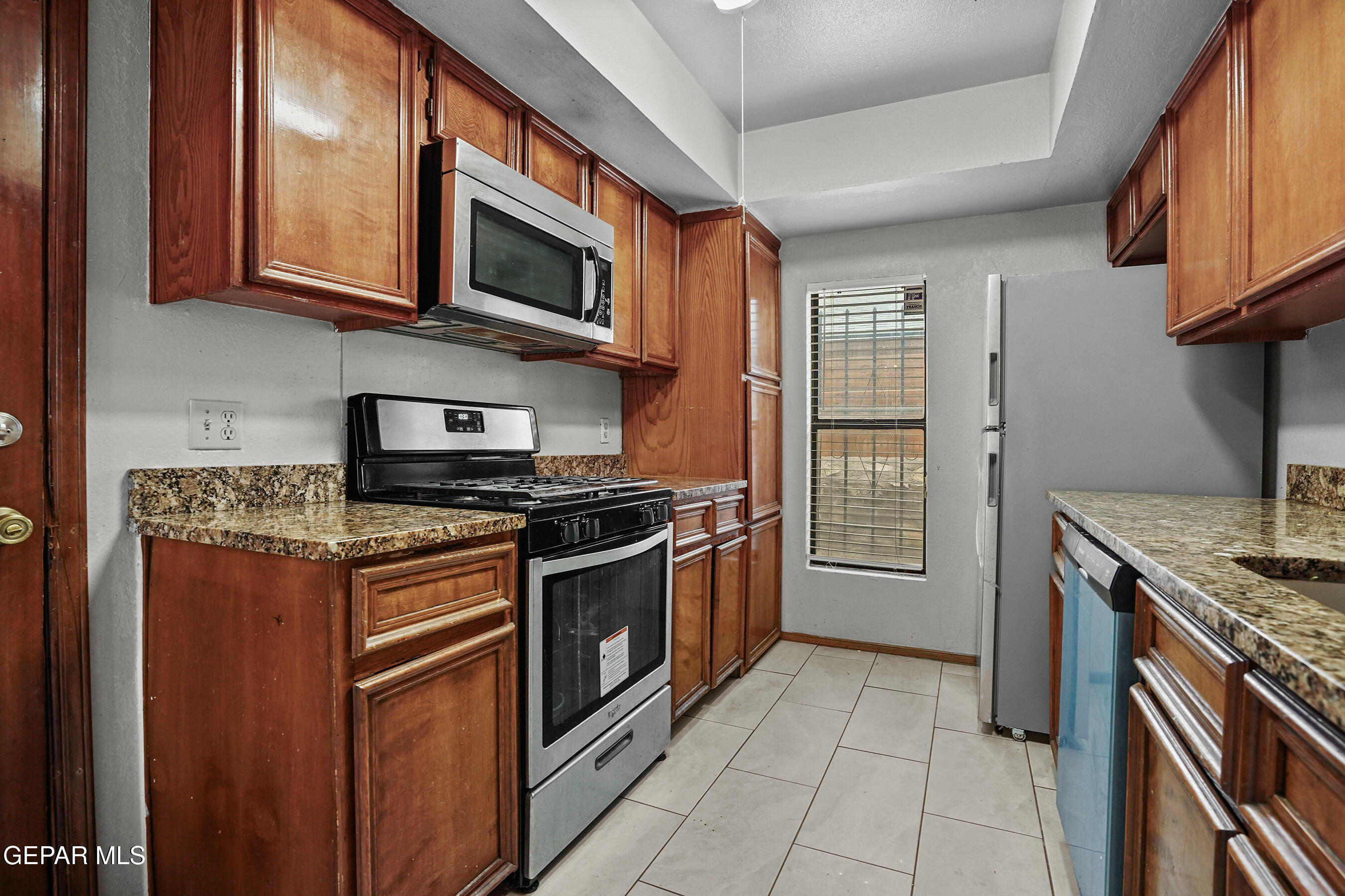6900 Ridge Top Drive El Paso, TX 79904 - Photo 12 of 32 a kitchen with stainless steel appliances granite countertop a stove top oven microwave and cabinets