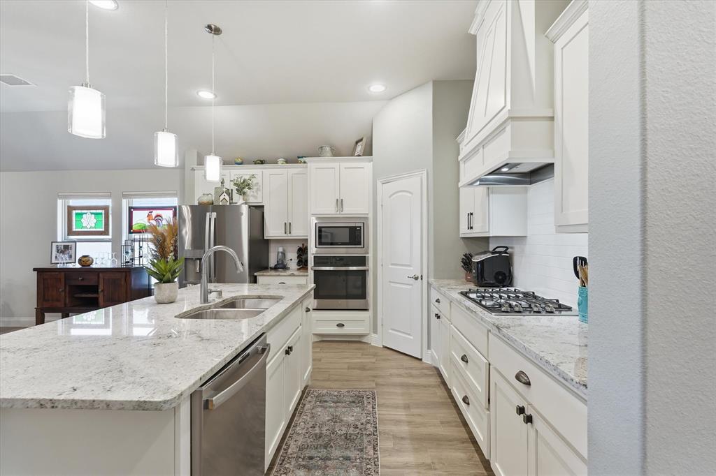 813 Mildren Lane Fate, TX 75087 - Photo 6 of 32 The kitchen offers stainless appliances, a spacious island, walk-in pantry, built-in microwave and oven, a gas cooktop, and the side-by-side refrigerator conveys with sale of home!
