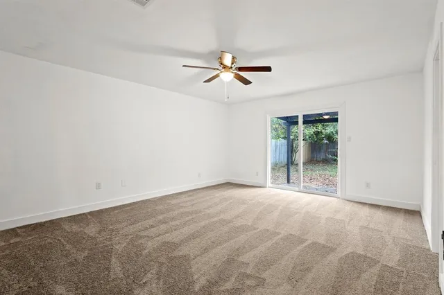 an empty room with chandelier fan and windows