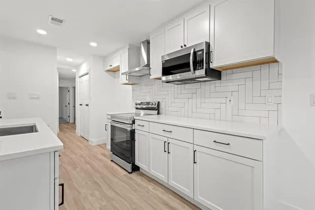 a kitchen with stainless steel appliances a stove microwave and sink