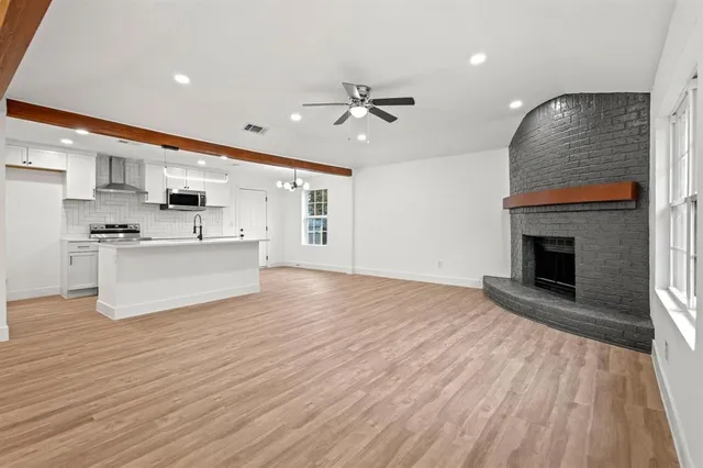 a view of kitchen with kitchen island wooden floor and stainless steel appliances