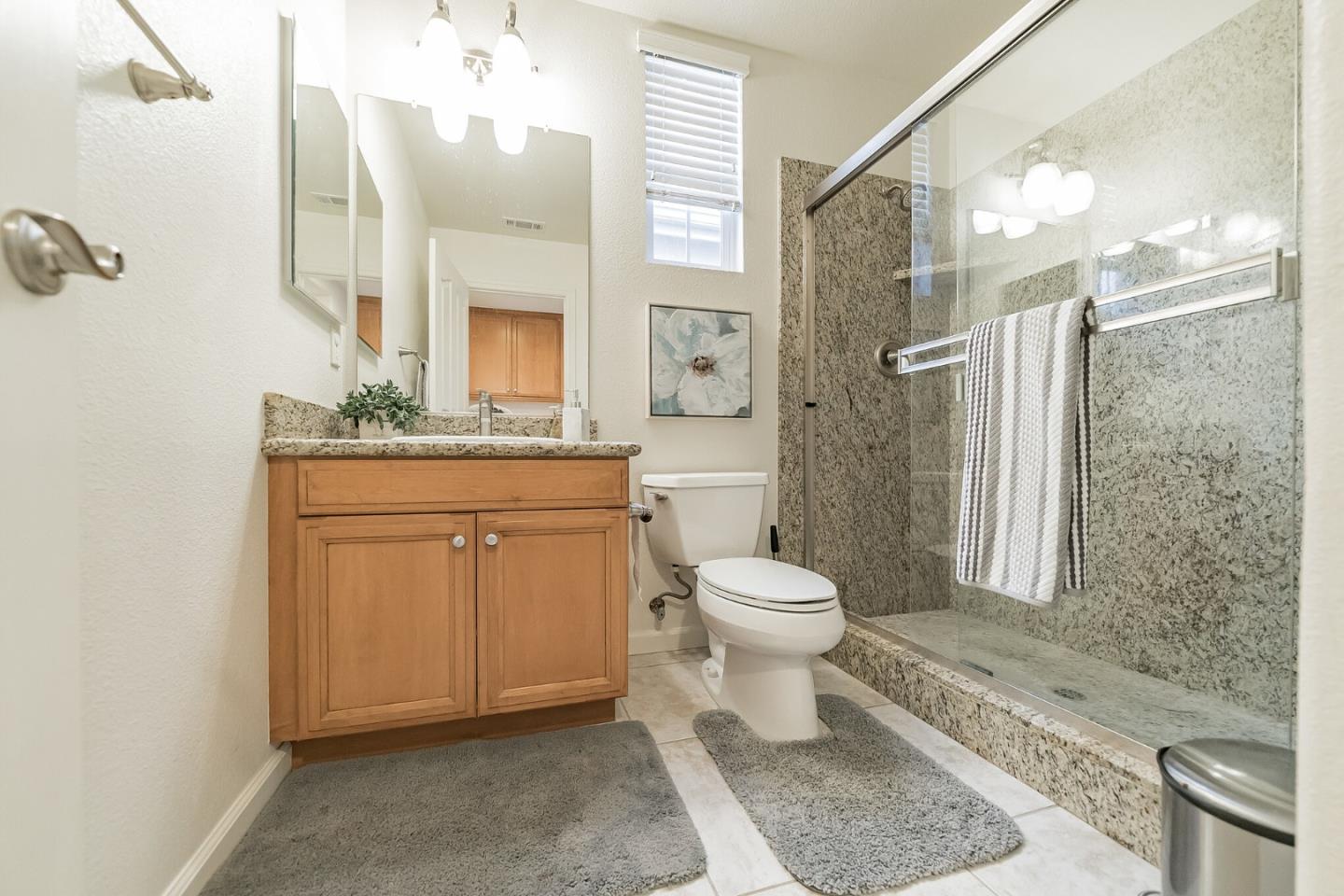 3830 Highbury Way San Ramon, CA 94582 - Photo 12 of 38 a bathroom with a granite countertop toilet a sink a mirror and shower