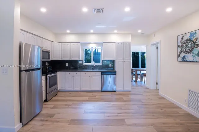 a large kitchen with stainless steel appliances granite countertop a refrigerator and a stove top oven