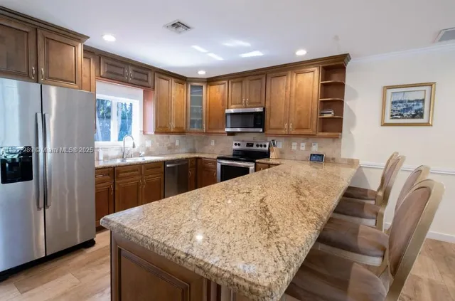 a kitchen with stainless steel appliances granite countertop a refrigerator a stove top oven a sink dishwasher and white cabinets