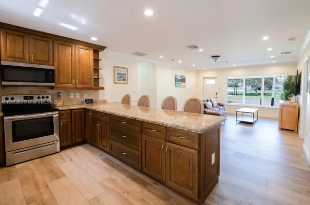 a large kitchen with stainless steel appliances granite countertop a large counter top a stove a sink and a refrigerator