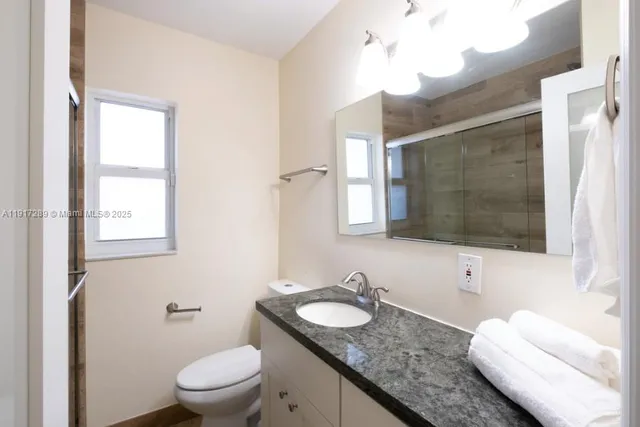 a bathroom with a granite countertop sink a toilet and a mirror