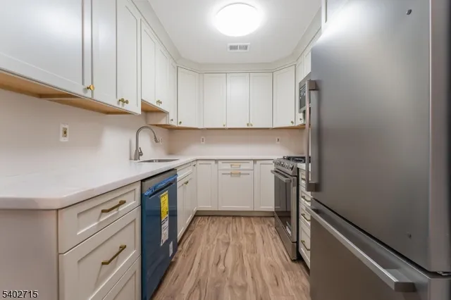 a kitchen with a sink cabinets stainless steel appliances and a window