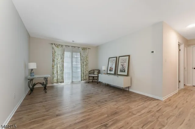 a view of an empty room with window wooden floor and a bedroom