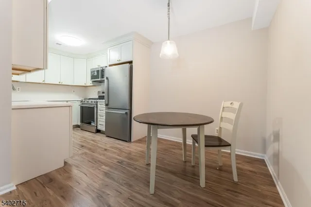 a kitchen with stainless steel appliances granite countertop a refrigerator a stove a microwave oven a sink with island and chairs with wooden floor