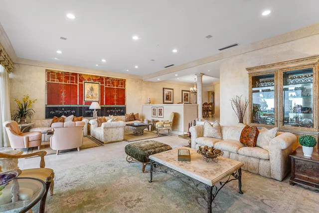 a living room with furniture kitchen view and large windows