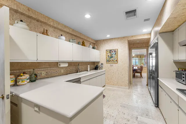 a large white kitchen with a sink and refrigerator