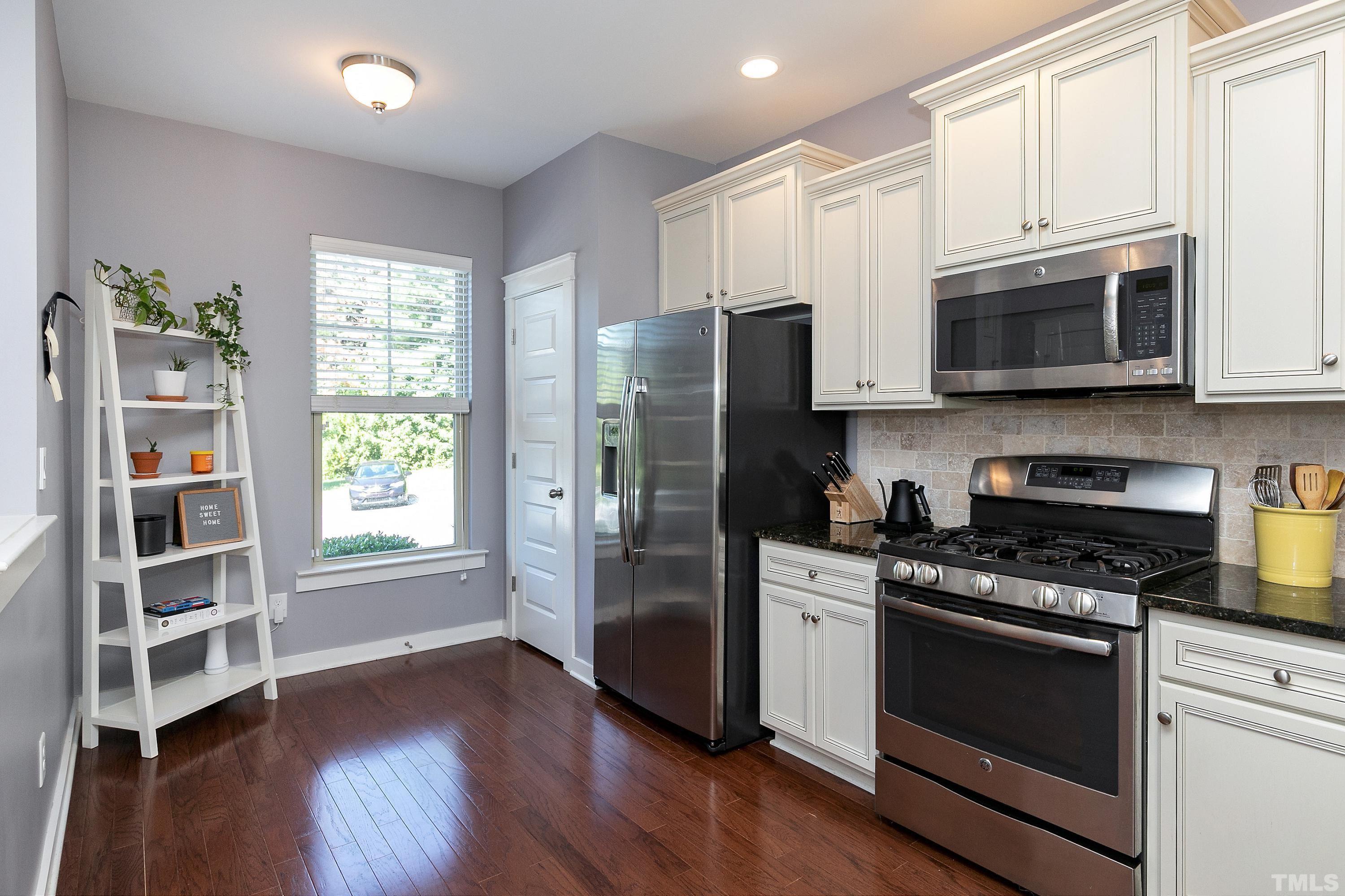 7906 Allscott Way Raleigh, NC 27612 - Photo 5 of 30 a kitchen with stainless steel appliances granite countertop a stove a refrigerator and a microwave
