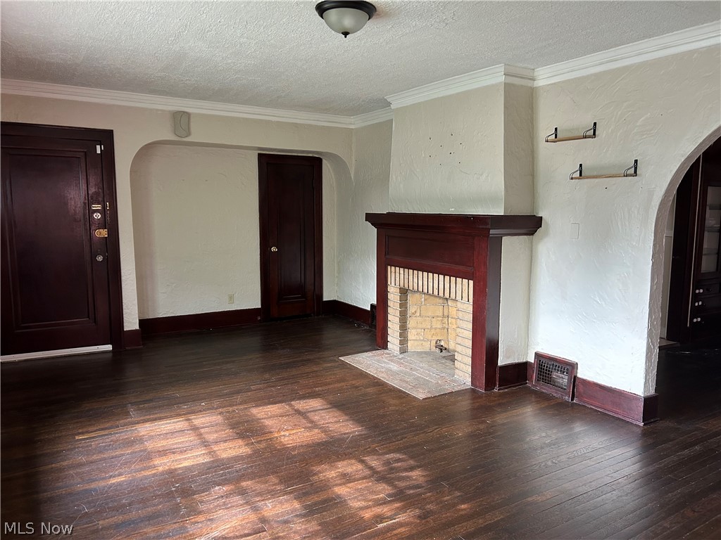 3658 Strathavon Road Cleveland, OH 44120 - Photo 4 of 16 Unfurnished living room featuring ornamental molding, a textured ceiling, and dark wood-type flooring