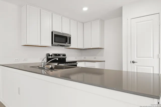 a kitchen with stainless steel appliances granite countertop a refrigerator a stove top oven a sink and dishwasher with wooden floor