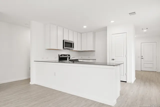 a large white kitchen with wooden floors and a fireplace