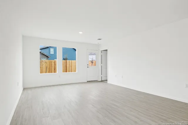 a view of an empty room with wooden floor and window