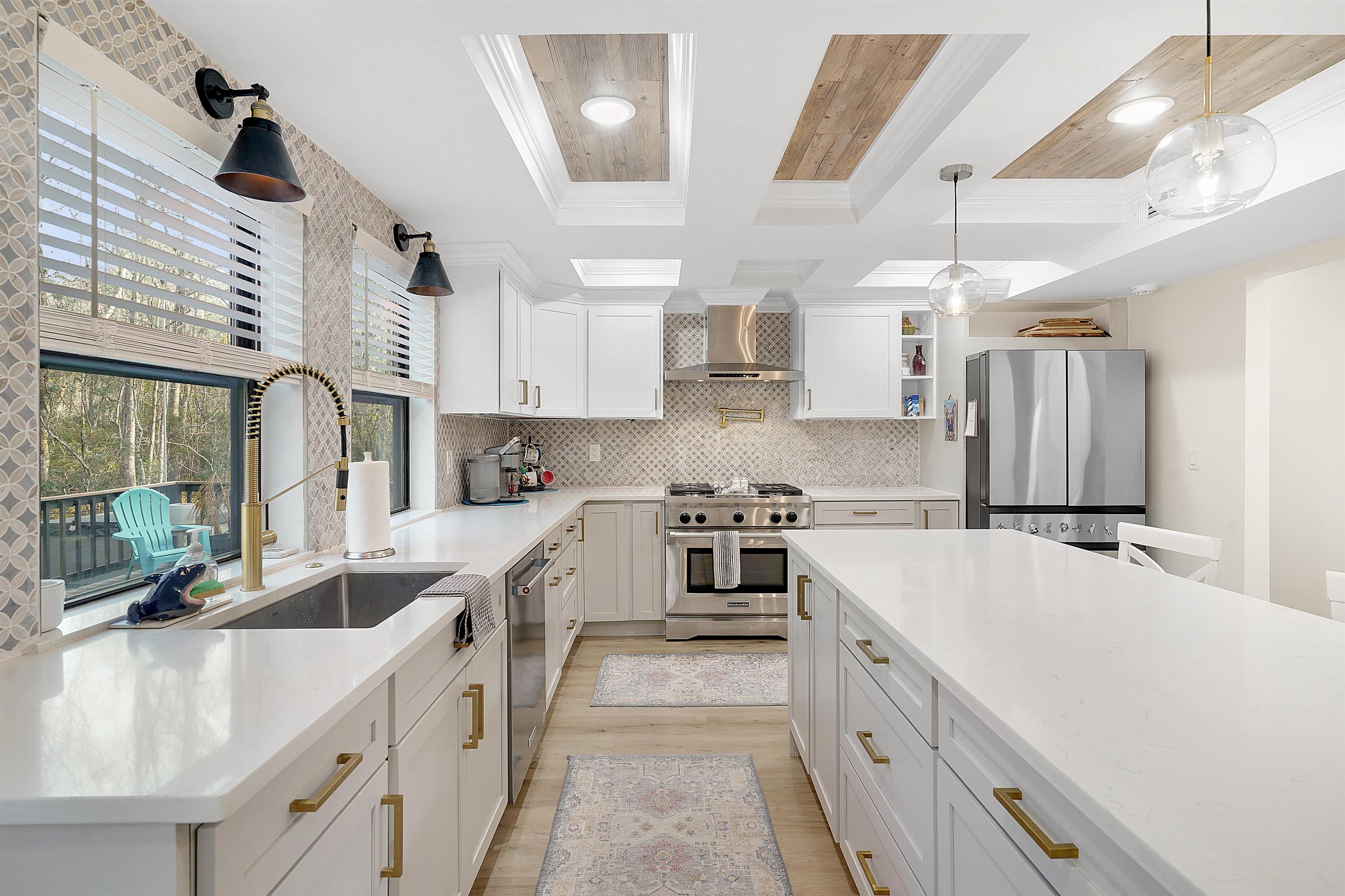 3020 Mac Road St. Augustine, FL 32086 - Photo 14 of 49 Kitchen featuring decorative light fixtures, stainless steel appliances, white cabinetry, light wood-style floors, and backsplash