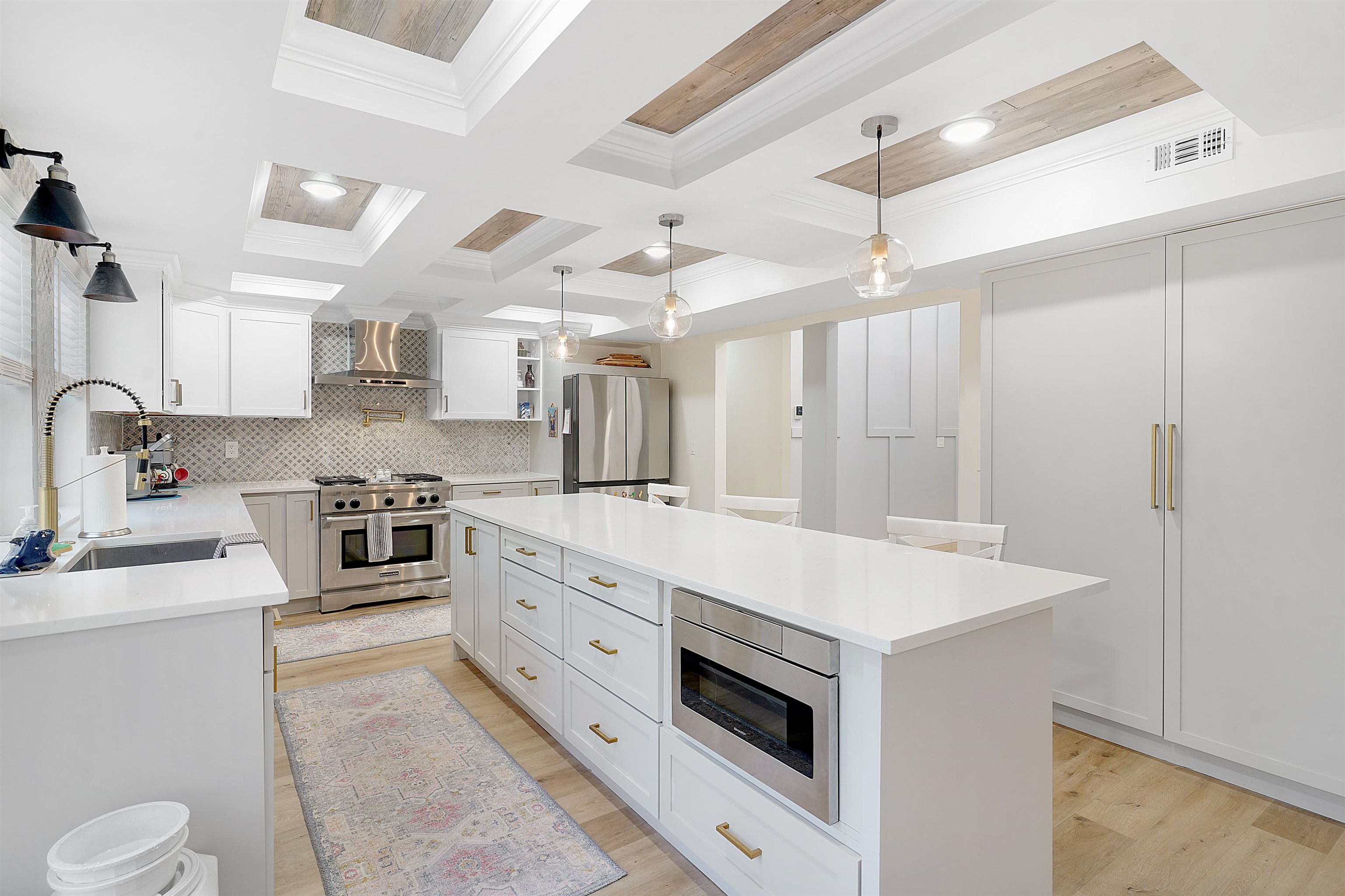 3020 Mac Road St. Augustine, FL 32086 - Photo 15 of 49 Kitchen with stainless steel appliances, hanging light fixtures, coffered ceiling, light wood finished floors, and white cabinetry