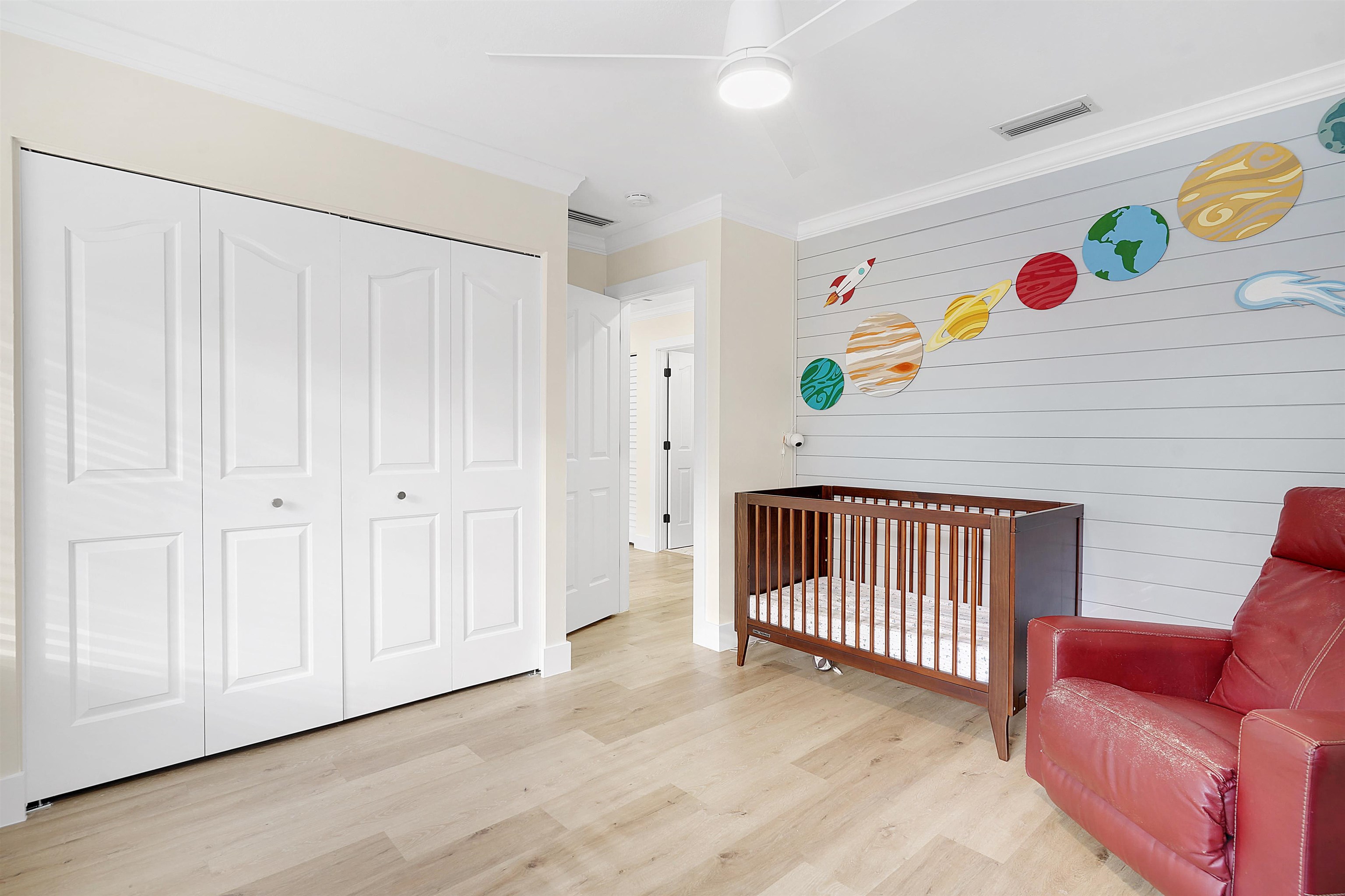 3020 Mac Road St. Augustine, FL 32086 - Photo 33 of 49 Bedroom with crown molding, a nursery area, light wood finished floors, a closet, and wood walls