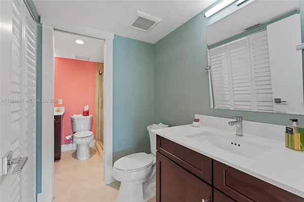 a bathroom with a sink a toilet a mirror and shower
