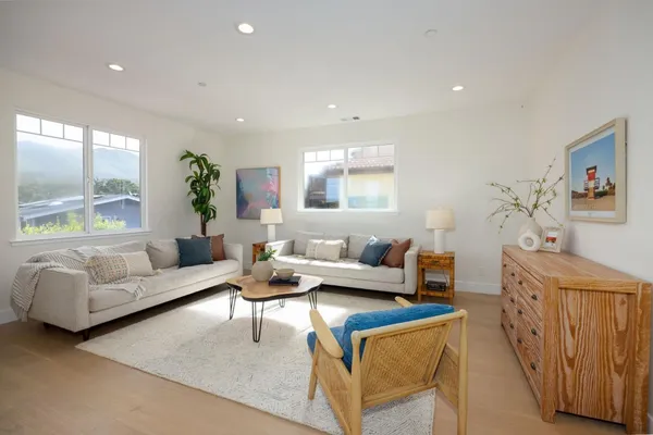 a living room with furniture kitchen view and a wooden floor