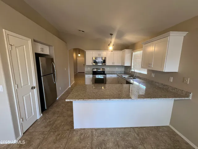 a large kitchen with granite countertop a sink a counter top space and cabinets