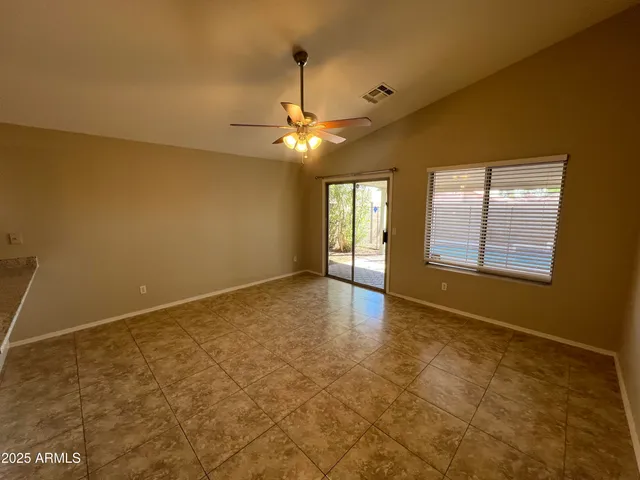 an empty room with chandelier fan and windows