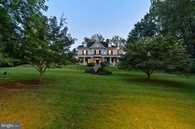 a view of a big house with a big yard and large trees