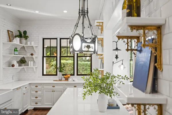 a kitchen with stainless steel appliances white cabinets a potted plant and a window