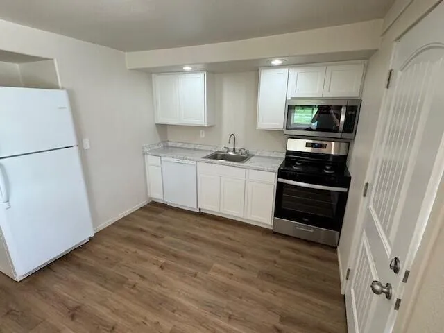 a kitchen with granite countertop a refrigerator and a stove top oven