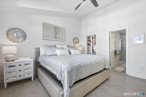 a spacious bedroom with a bed and a lamp on dresser