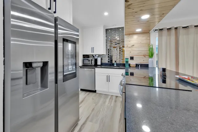 a kitchen with stainless steel appliances granite countertop a refrigerator a sink and a stove