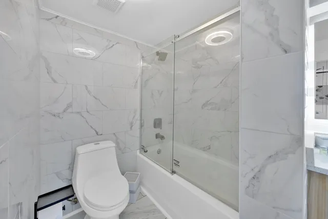 a white toilet sitting next to a bath tub and a shower