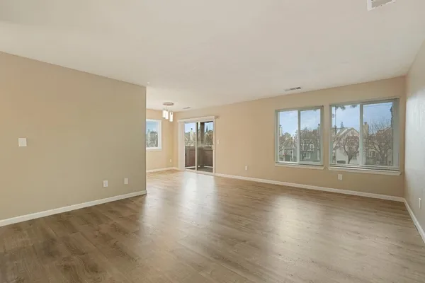 an empty room with wooden floor and windows