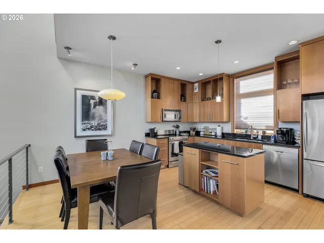 a kitchen with stainless steel appliances granite countertop a table chairs and a refrigerator