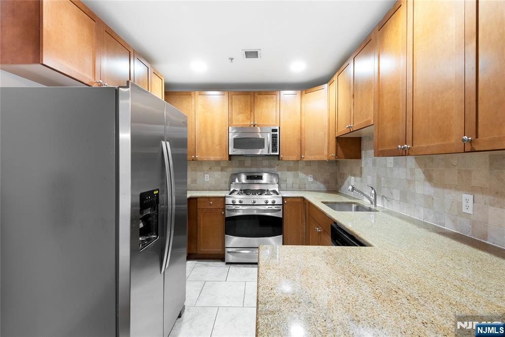 54 Polifly Road, Unit 311 Hackensack, NJ 07601 - Photo 7 of 20 a kitchen with stainless steel appliances granite countertop a refrigerator a stove and a sink
