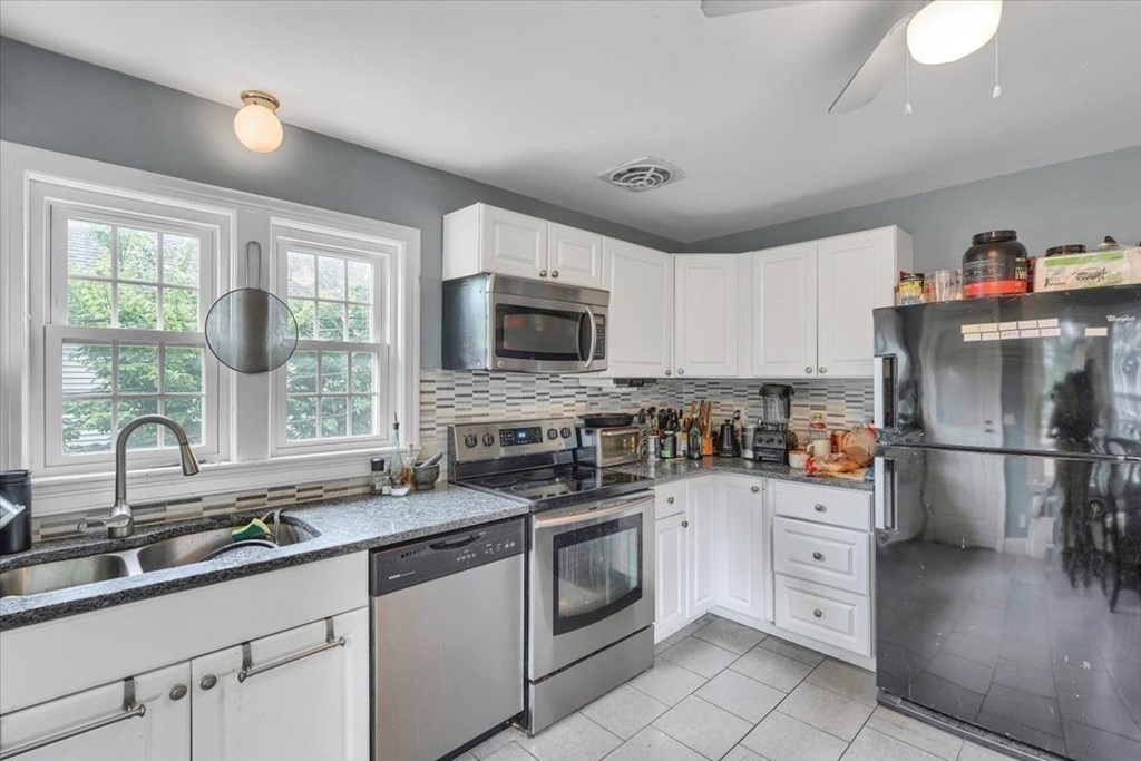 a kitchen with a sink white cabinets and stainless steel appliances