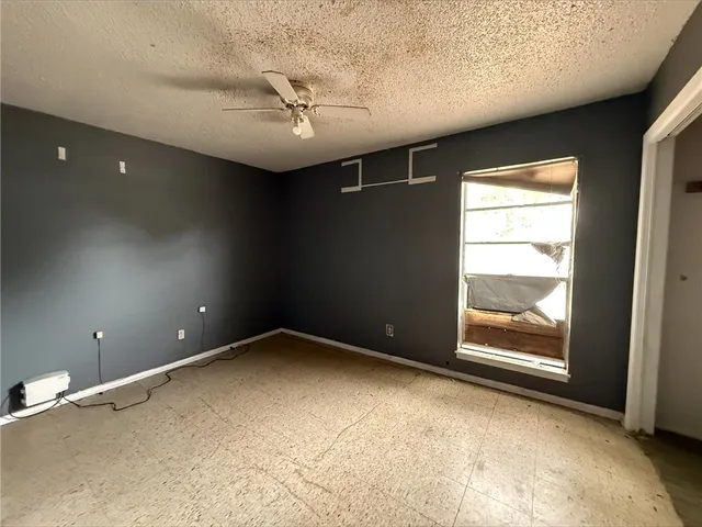 en empty room with windows and ceiling fan