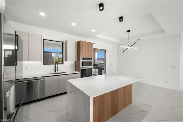 a large kitchen with stainless steel appliances a sink and a refrigerator