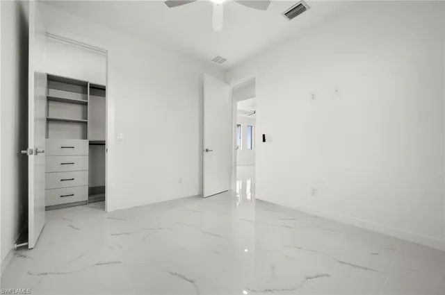 an empty room with a window and a ceiling fan