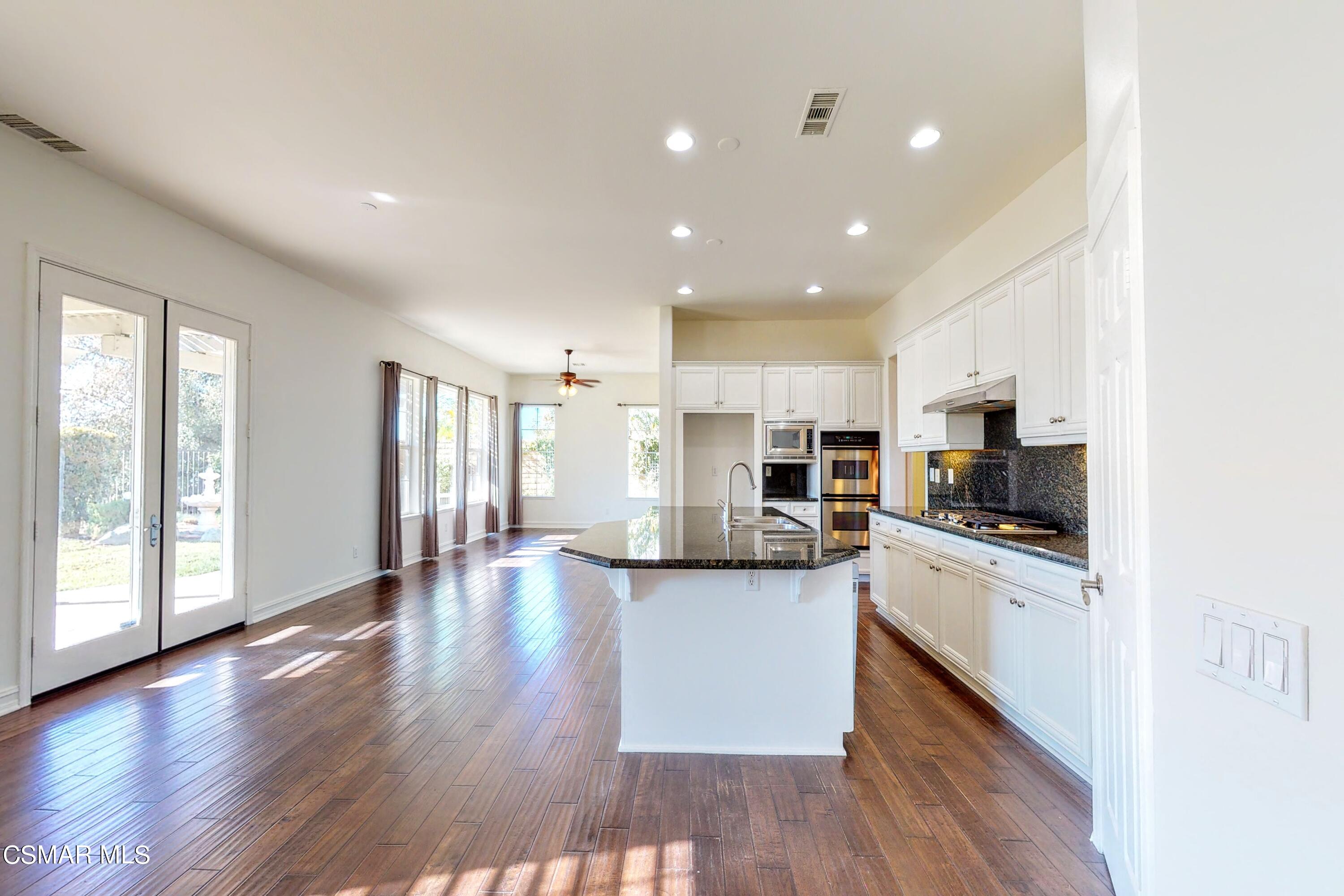 3705 Horizon Ridge Court Simi Valley, CA 93063 - Photo 15 of 62 a kitchen with stainless steel appliances kitchen island granite countertop a stove top oven a sink a dining table and chairs with wooden floor