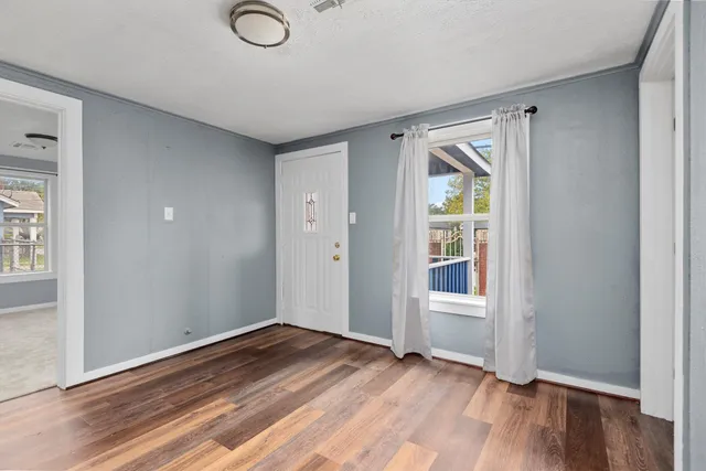 an empty room with wooden floor and windows