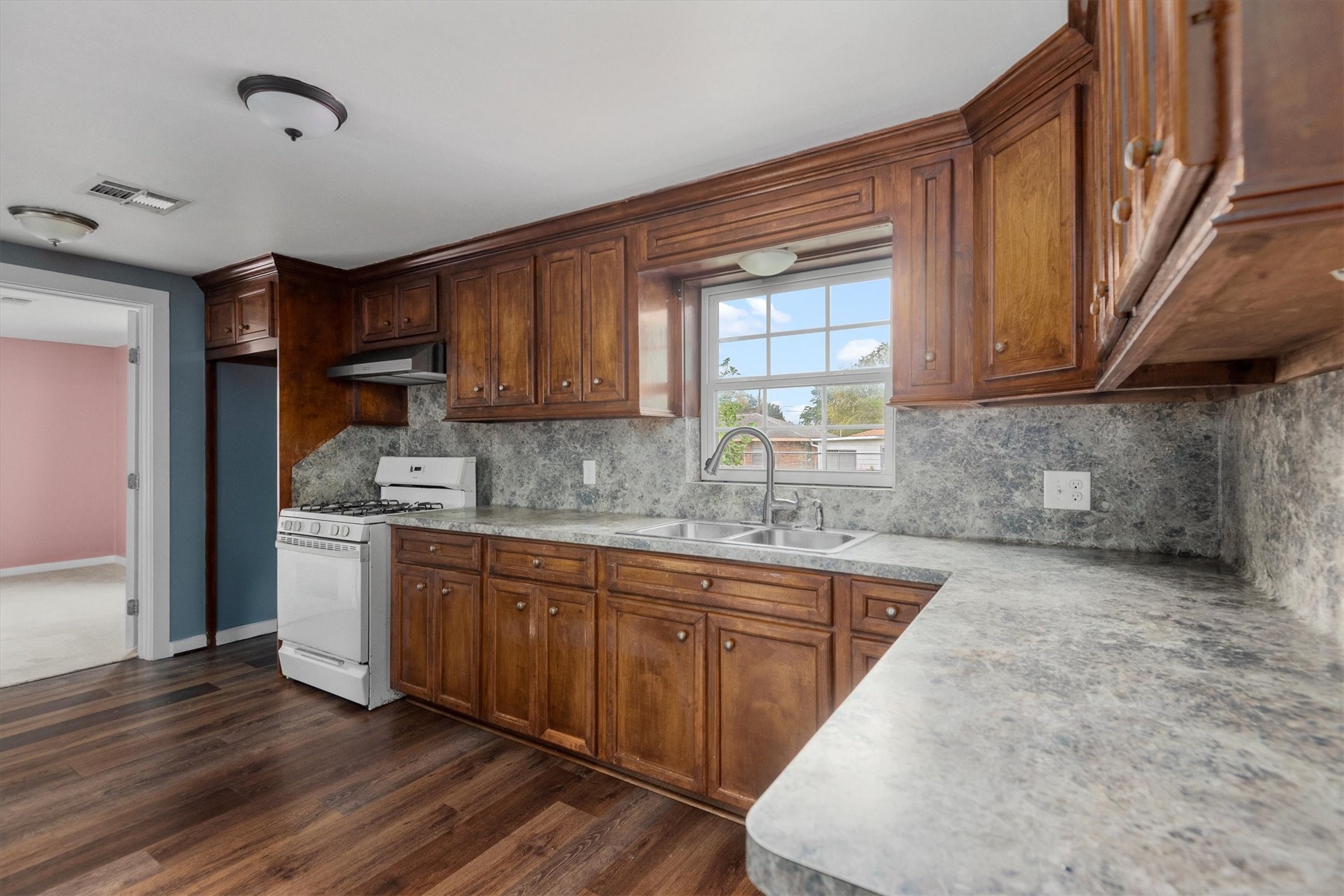 3914 Cetti Street Houston, TX 77009 - Photo 7 of 22 a kitchen with stainless steel appliances granite countertop wooden cabinets a sink and dishwasher a stove with wooden floor