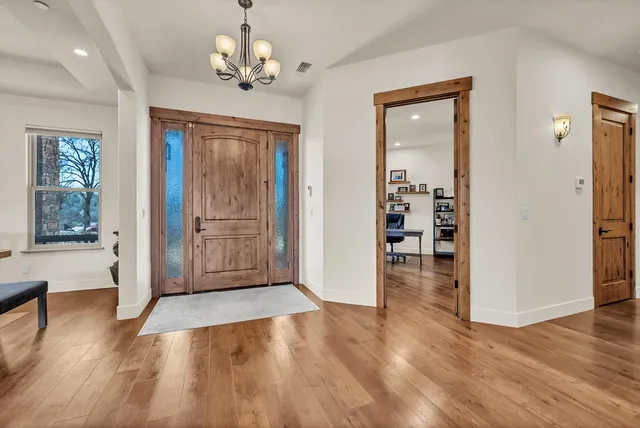 a kitchen with stainless steel appliances kitchen island granite countertop a stove top oven a sink a dining table and chairs with wooden floor