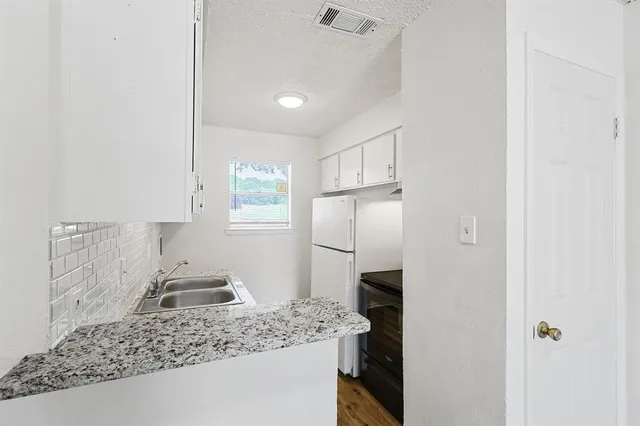 a kitchen with a sink a refrigerator and cabinets