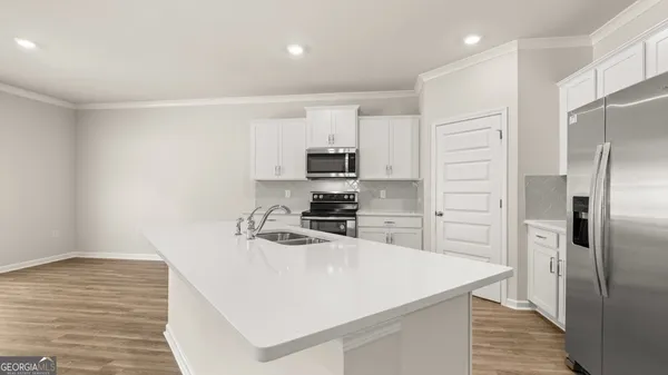 a kitchen with kitchen island a counter top space cabinets stainless steel appliances and wooden floor