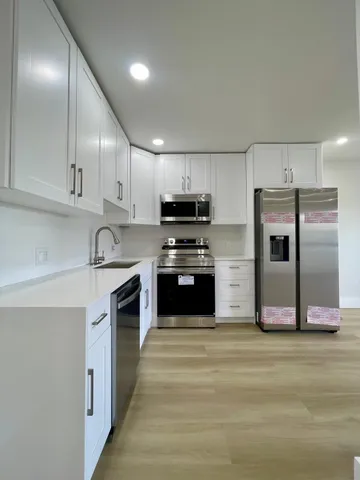 a kitchen with granite countertop a refrigerator stove and sink
