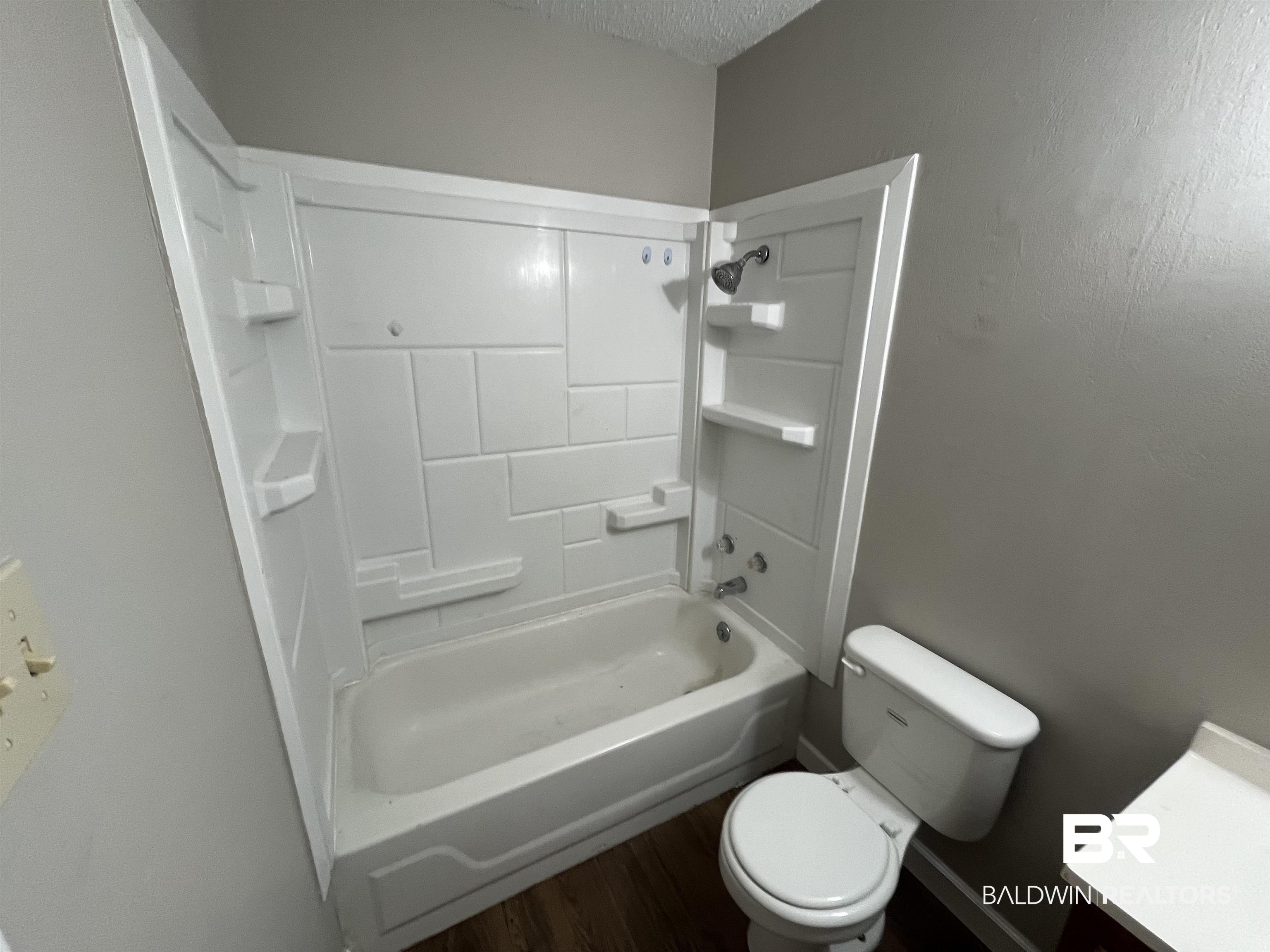 103 Roadway Street Brewton, AL 36426 - Photo 9 of 13 Full bathroom with wood-type flooring, a textured ceiling, shower combination, toilet, and vanity